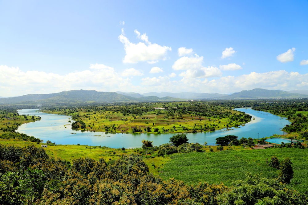 green grass field near lake under blue sky during daytime