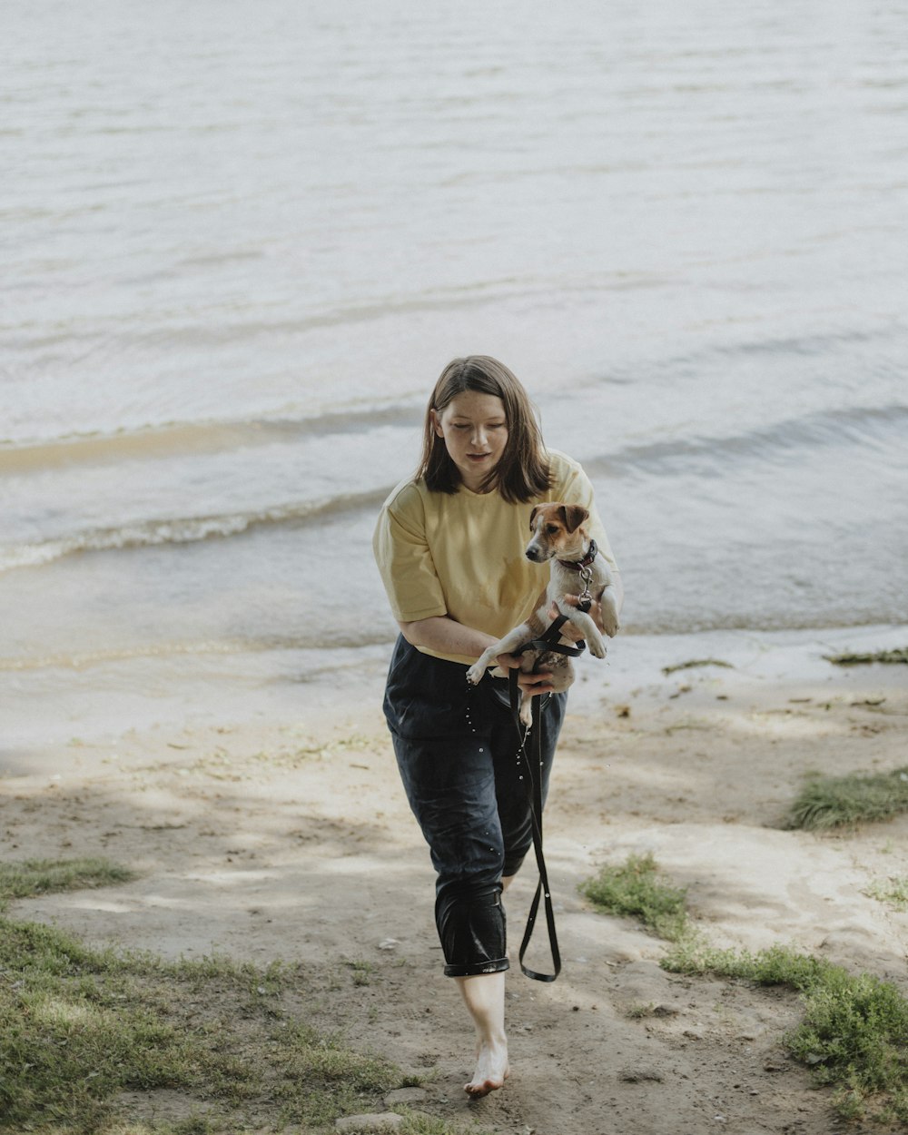 woman in beige long sleeve shirt and blue denim jeans holding dog leash