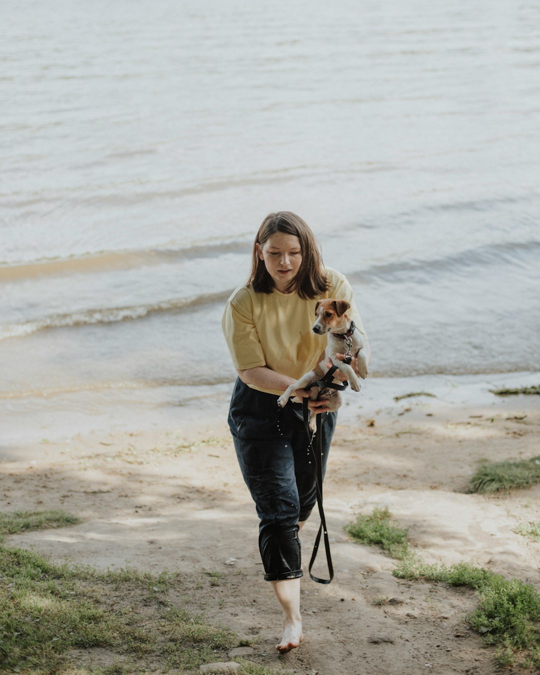 woman in beige long sleeve shirt and blue denim jeans holding dog leash