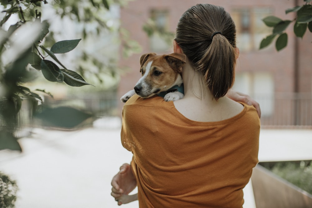 woman in orange shirt holding green plant