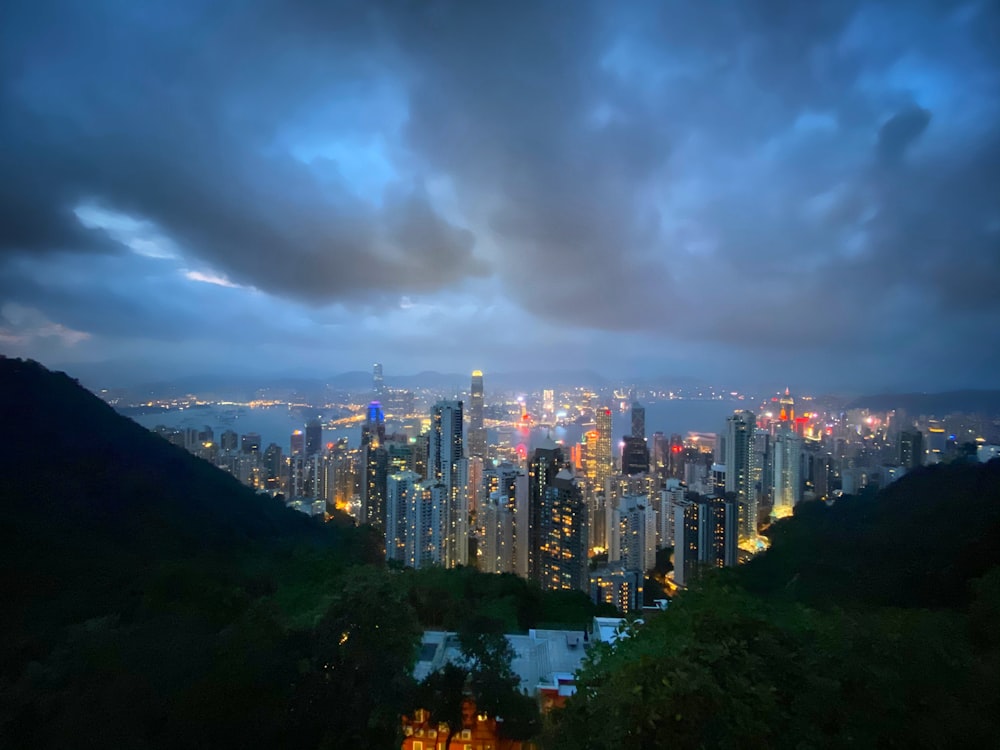 city skyline under gray cloudy sky during night time