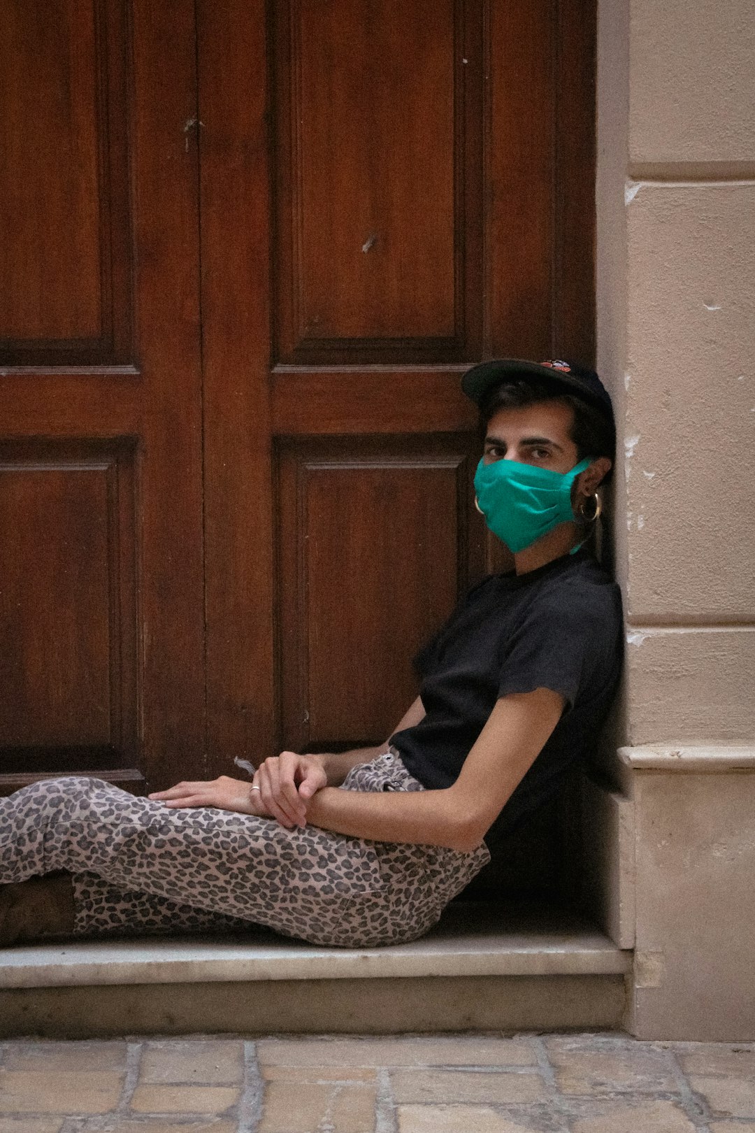 woman in blue and white dress wearing blue mask sitting on brown wooden bench