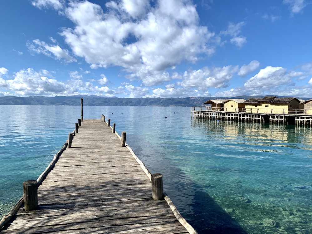 brown wooden dock on blue sea under blue and white cloudy sky during daytime