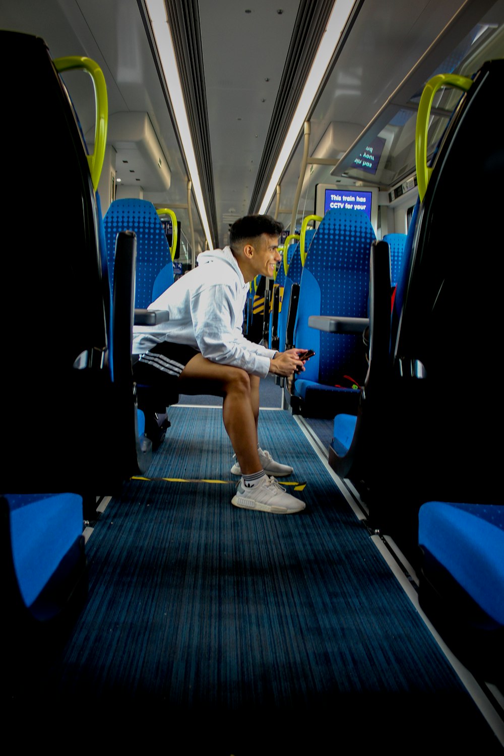 man in white t-shirt sitting on blue train seat