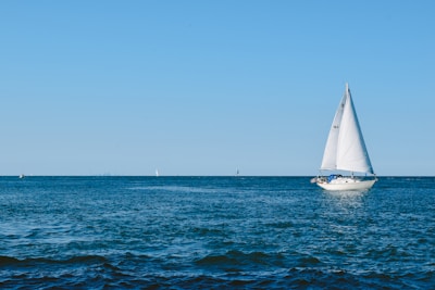 white sailboat on sea under blue sky during daytime