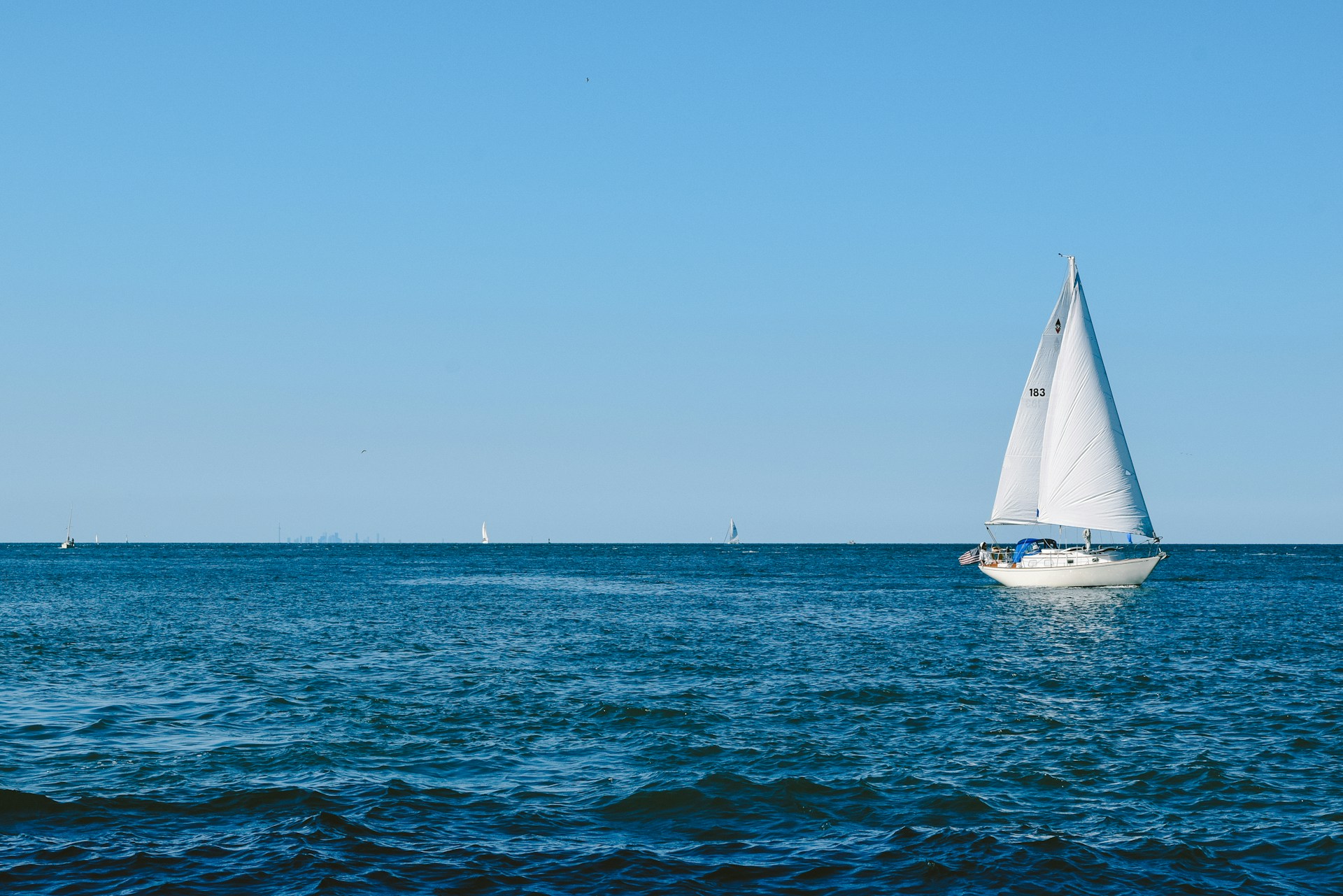 white sailboat on sea under blue sky during daytime