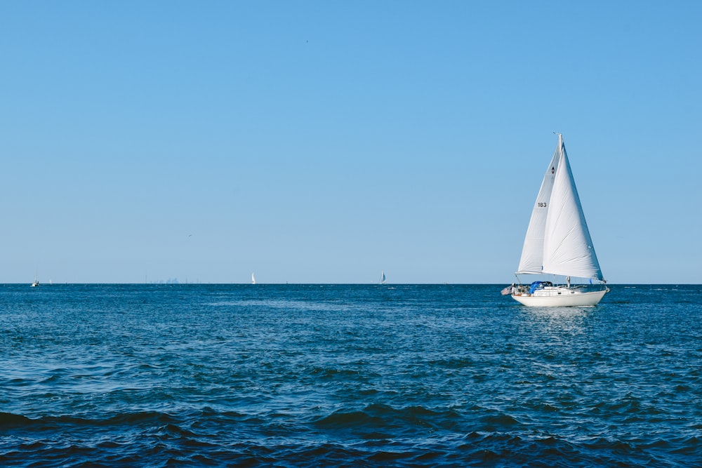 weißes Segelboot auf See unter blauem Himmel tagsüber