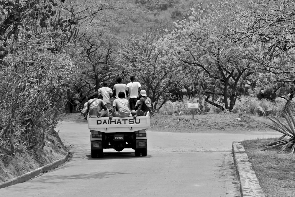 grayscale photo of man and woman riding on truck