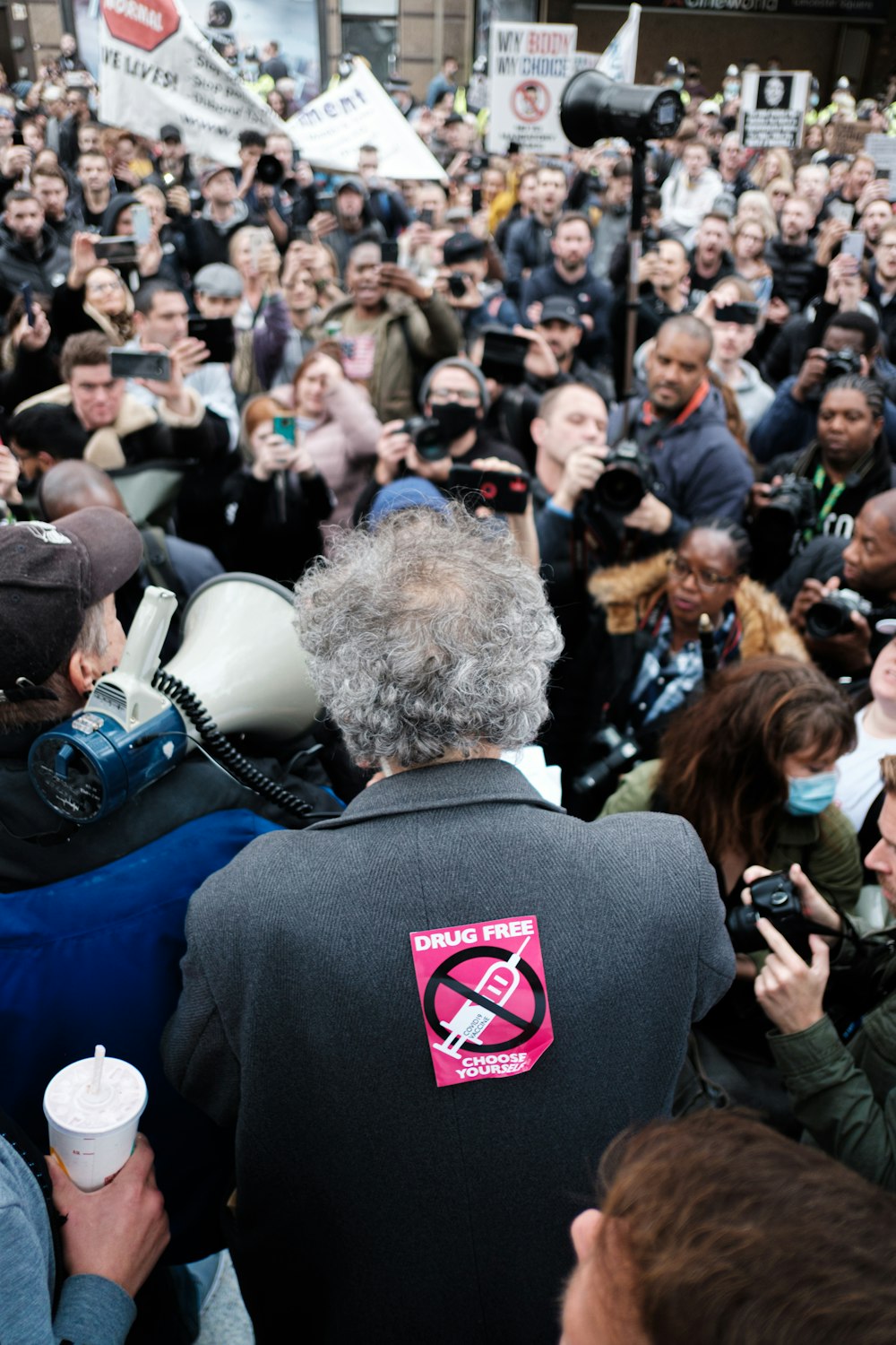 hombre con sudadera con capucha negra y roja de pie frente a la gente