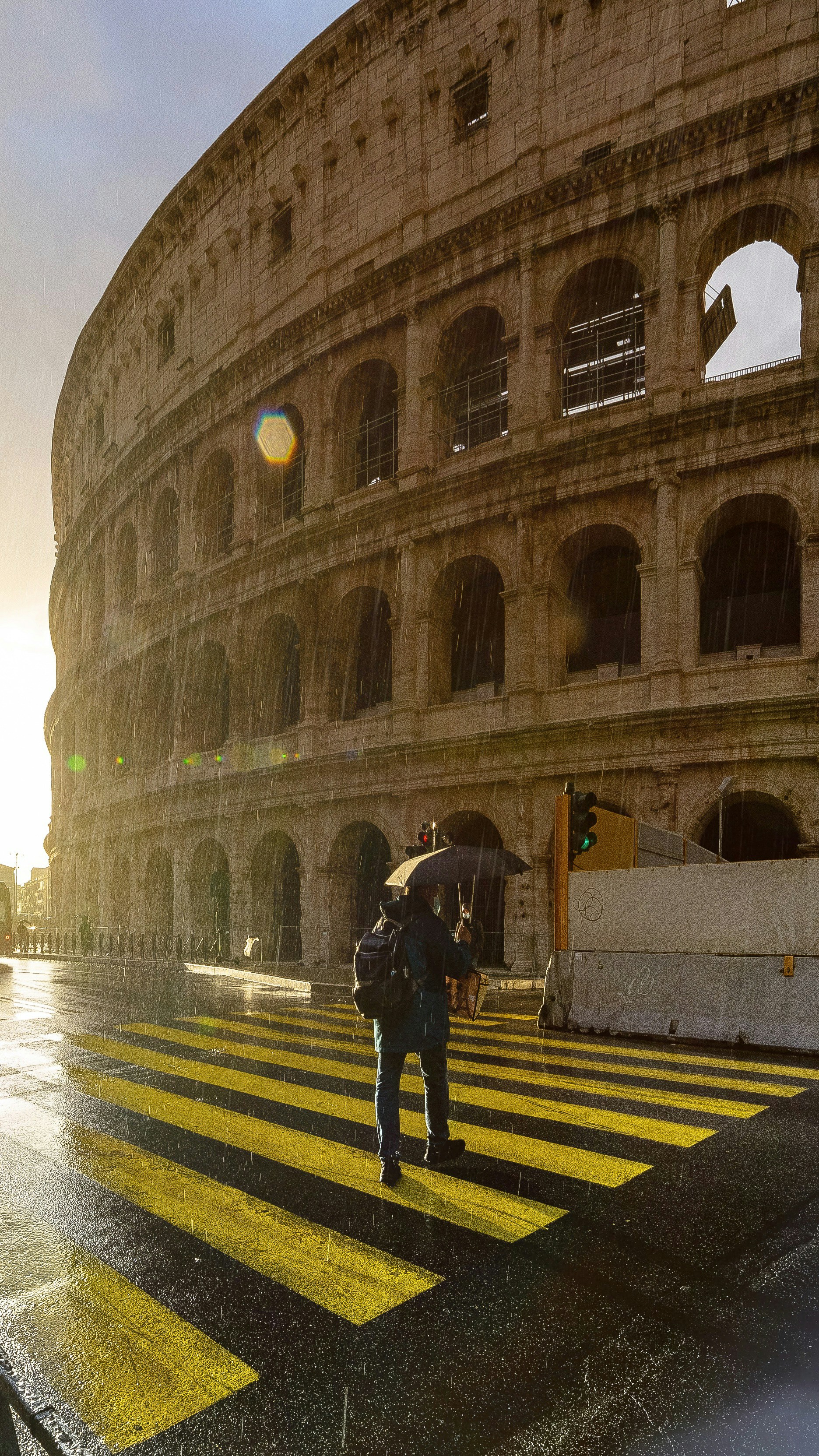 uomo in giacca nera e pantaloni neri che cammina sulla corsia pedonale durante la notte