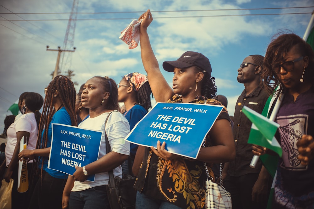 people standing and holding blue and white banner during daytime