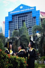 people wearing academic dress standing near blue building during daytime