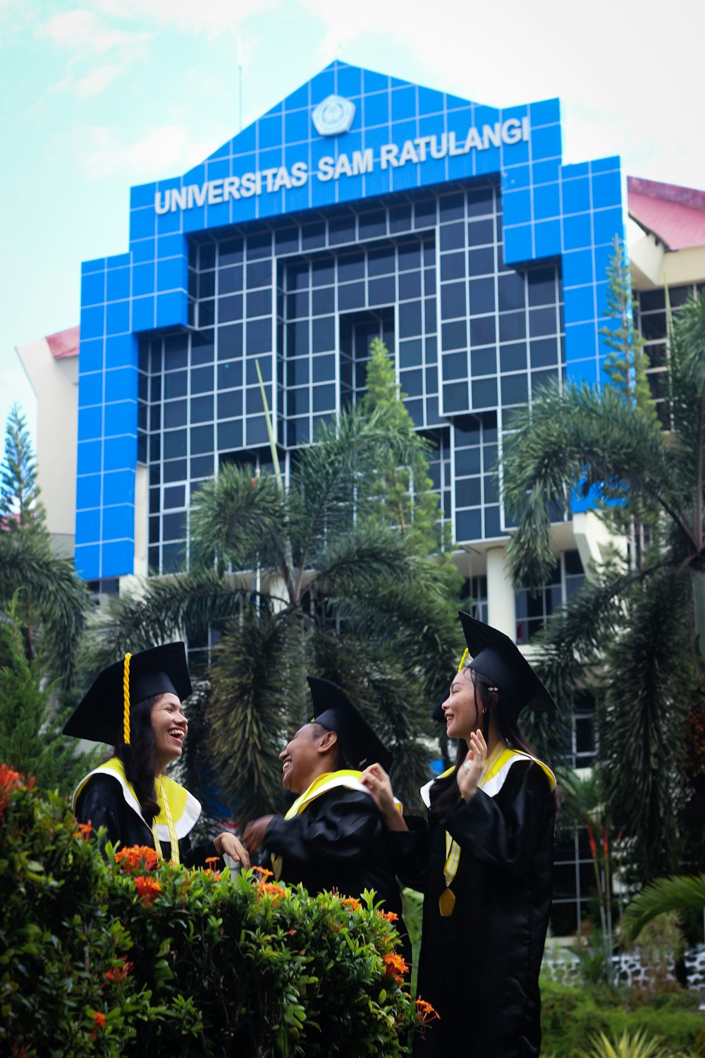 people wearing academic dress standing near blue building during daytime