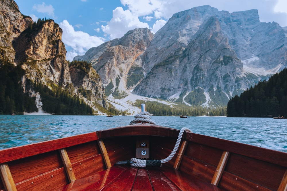 brown wooden boat on lake near snow covered mountain during daytime