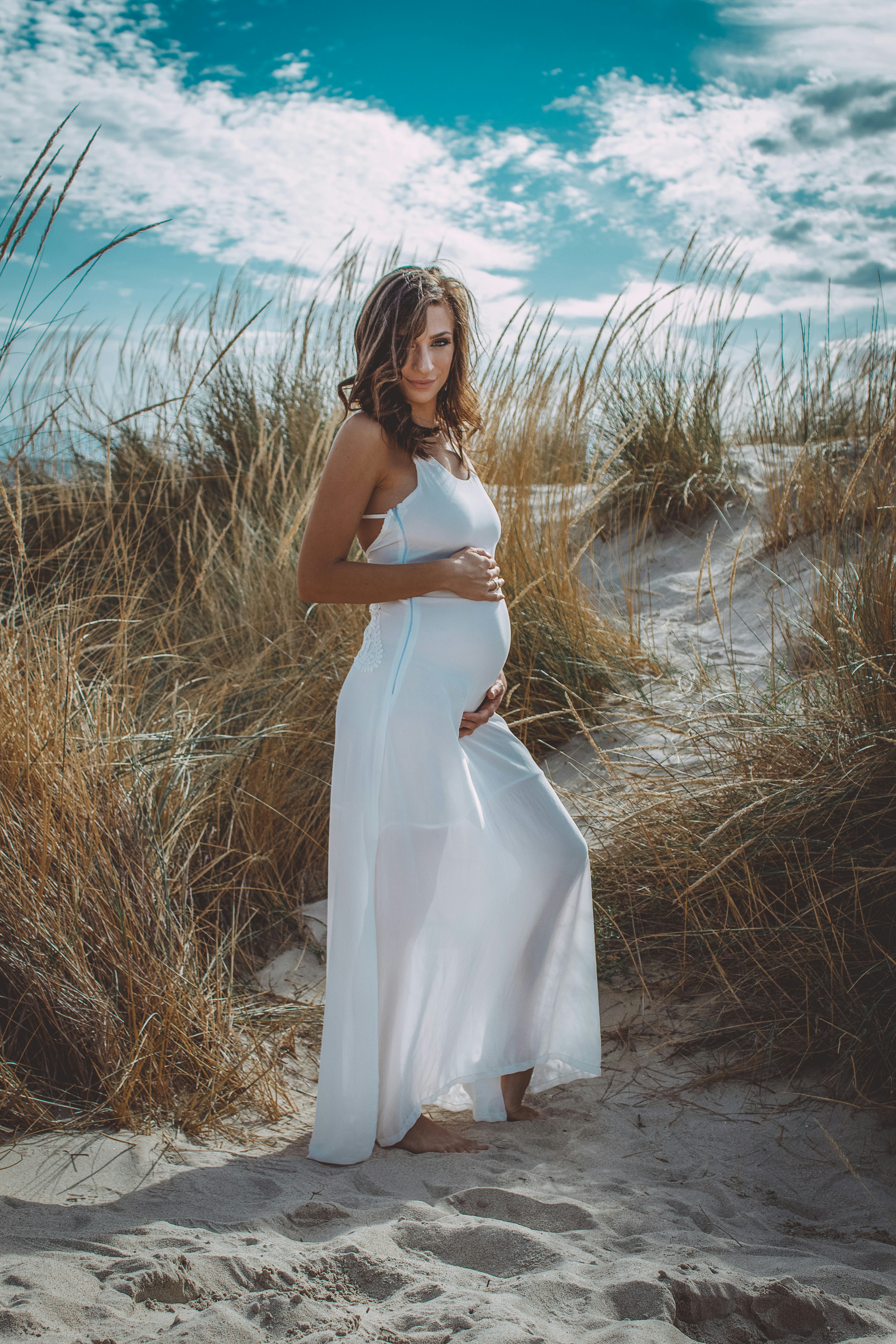 woman in white dress standing on brown grass field during daytime