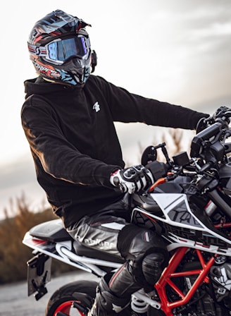 man in black jacket riding white and black sports bike