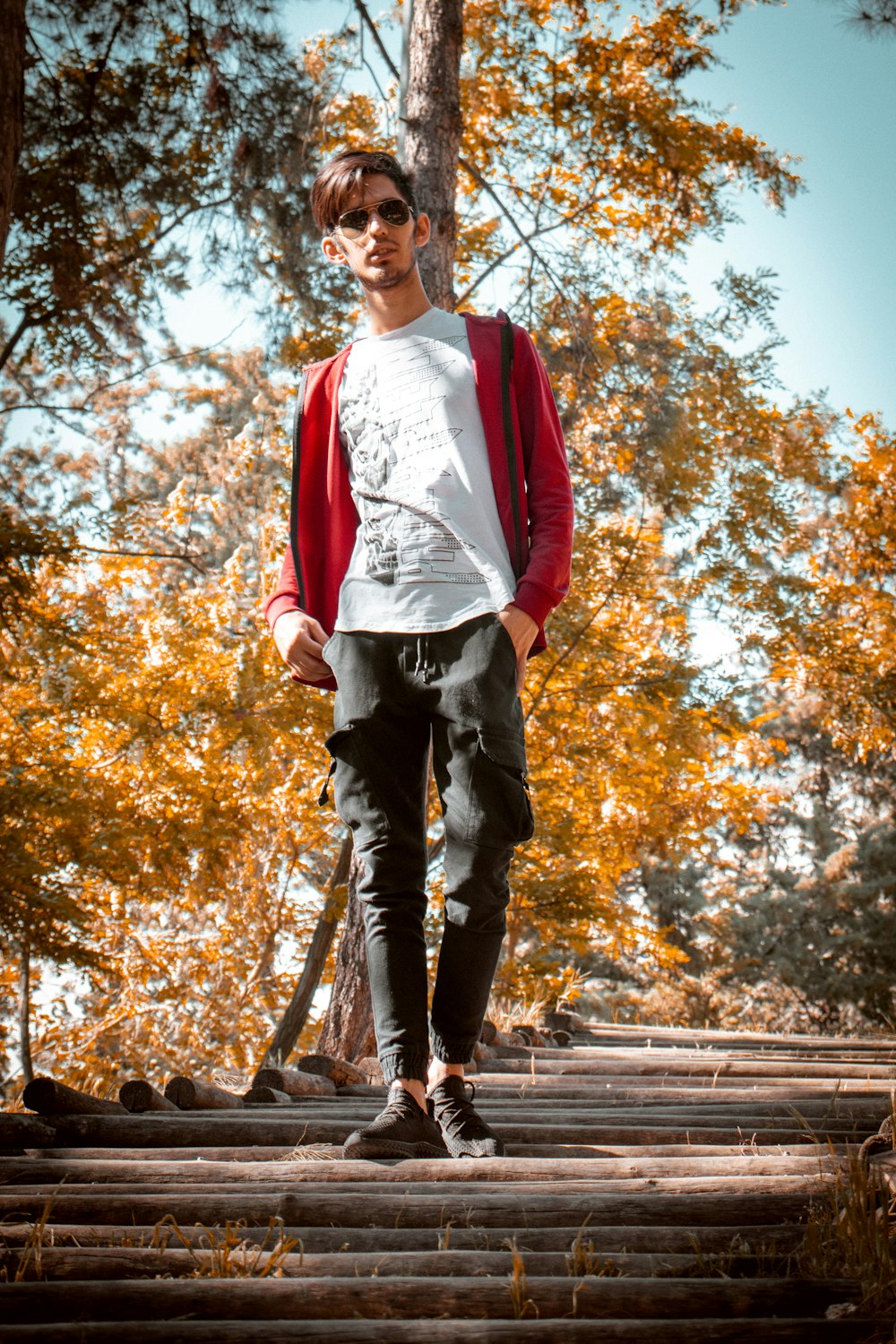 man in red and white long sleeve shirt standing on brown wooden pathway during daytime