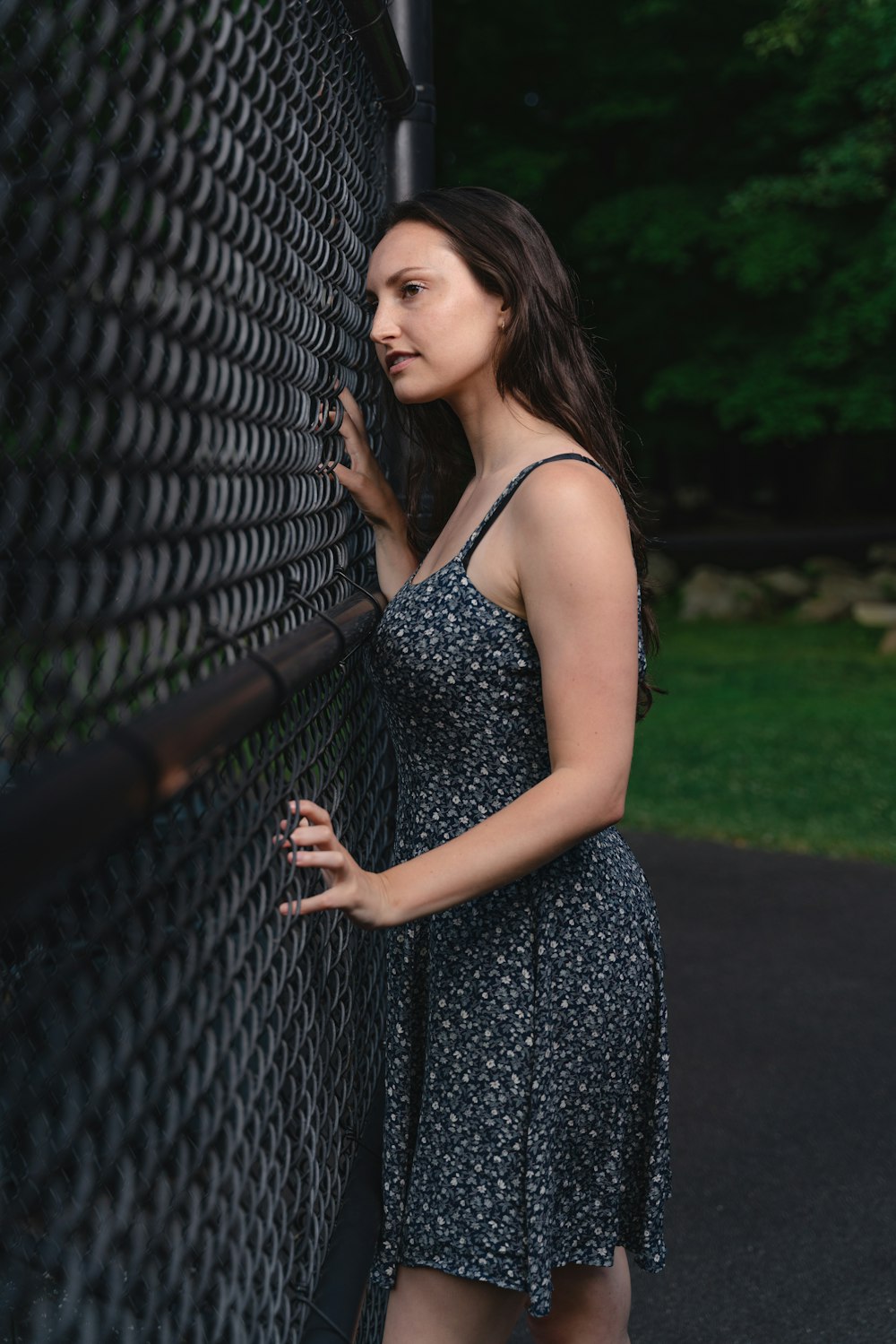 woman in black and white spaghetti strap dress standing beside black metal fence during daytime