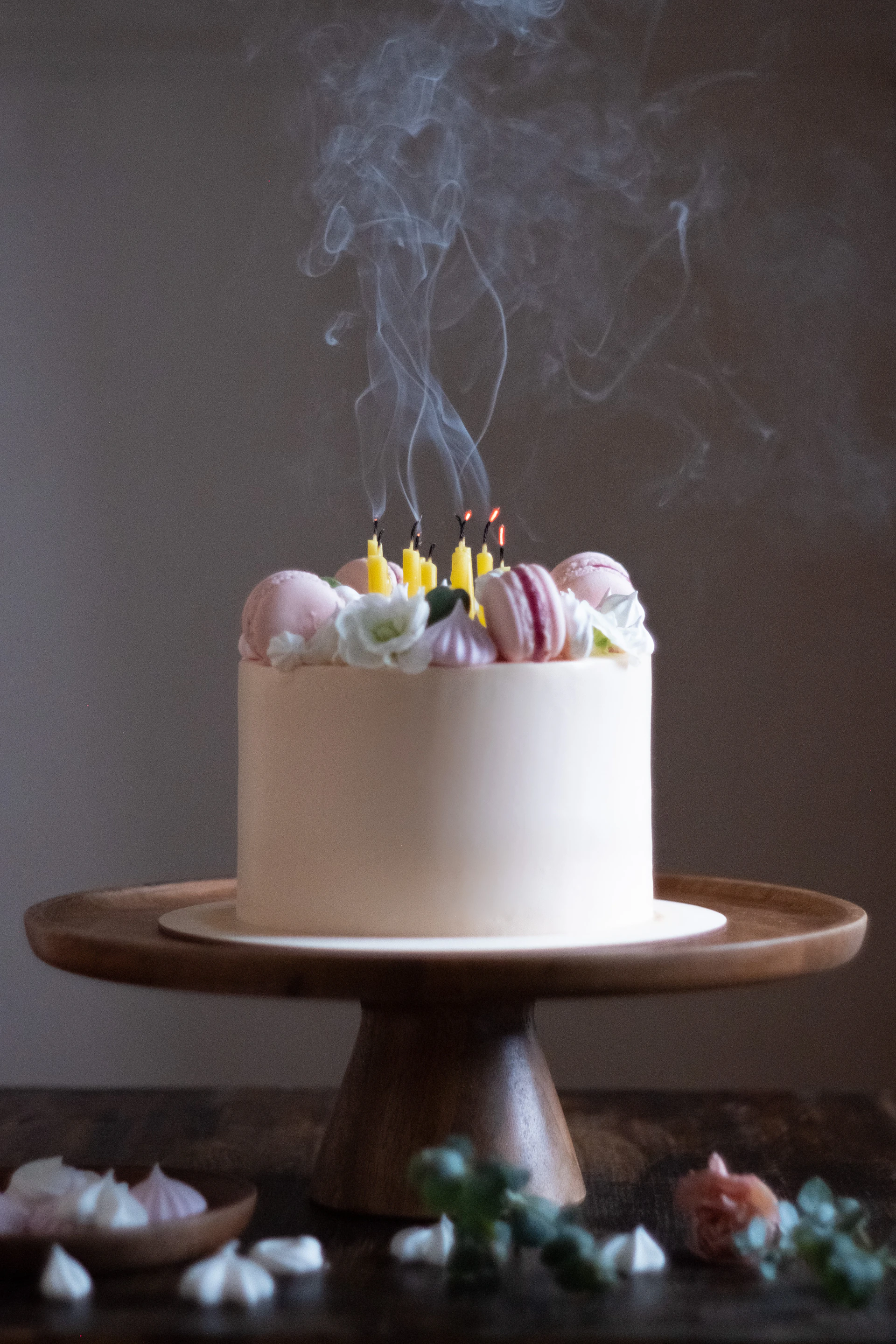 An elegant close-up of a birthday cake adorned with delicate blush and rose gold accents, surrounded by shimmering candles.
