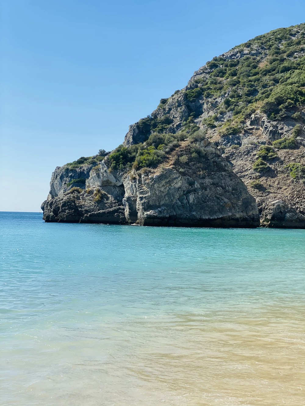 green and brown rock formation on sea during daytime