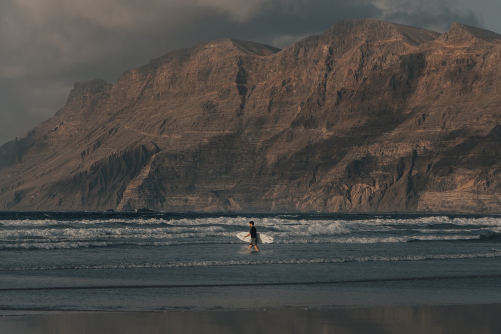 person in white shirt and black pants walking on beach during daytime