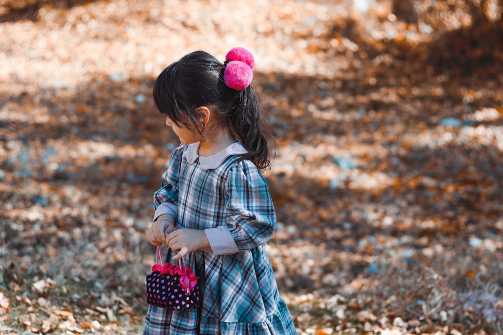 girl in white and blue plaid dress standing on brown dried leaves during daytime