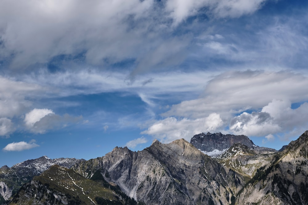 gray and white mountains under white clouds and blue sky during daytime