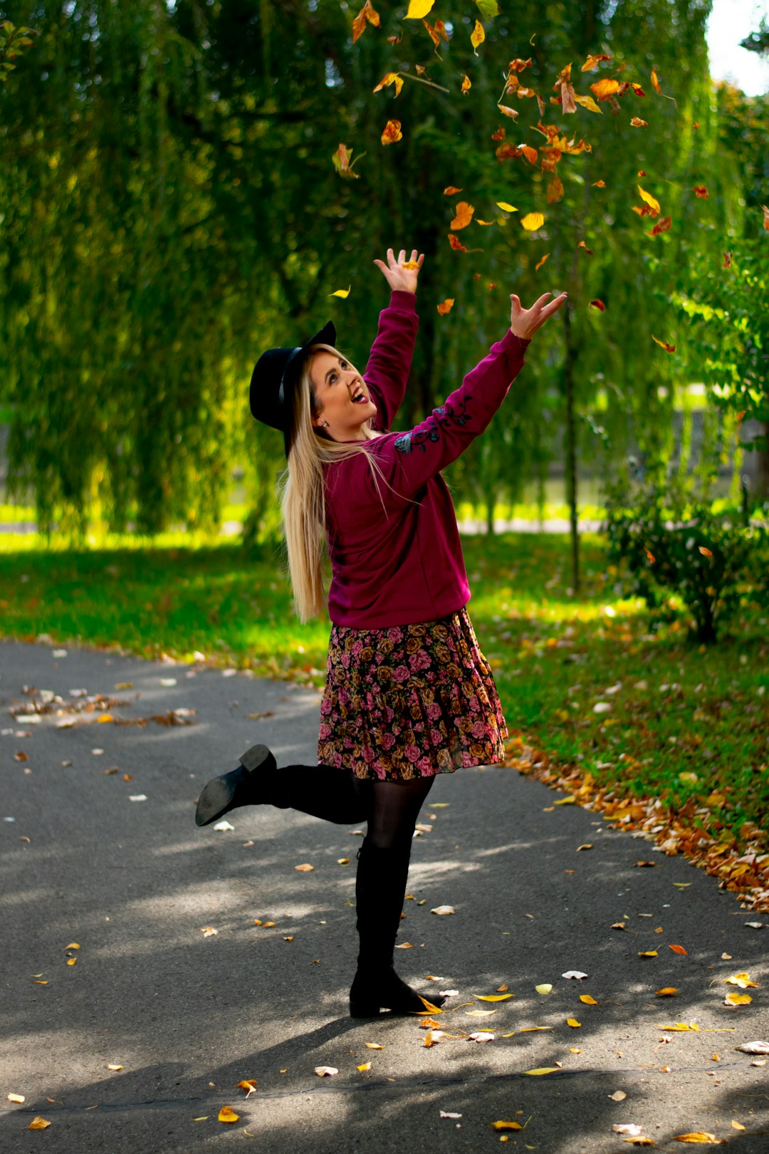 girl in pink long sleeve shirt and black skirt standing on gray concrete road during daytime