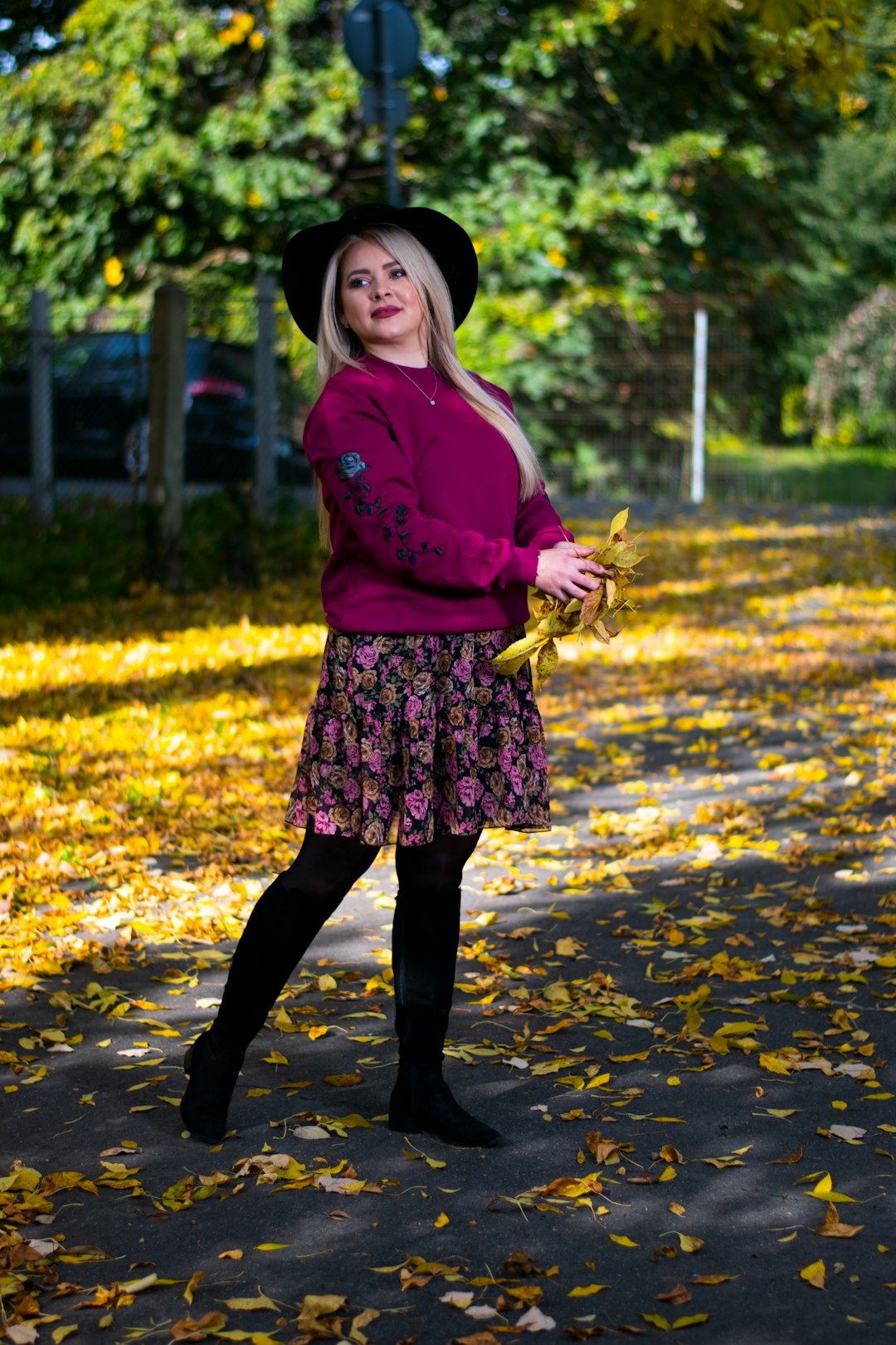 girl in pink long sleeve shirt and black skirt standing on yellow leaves on ground during