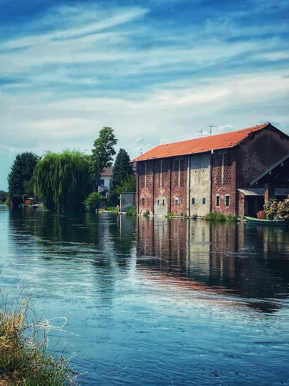 brown wooden house near green trees and body of water during daytime