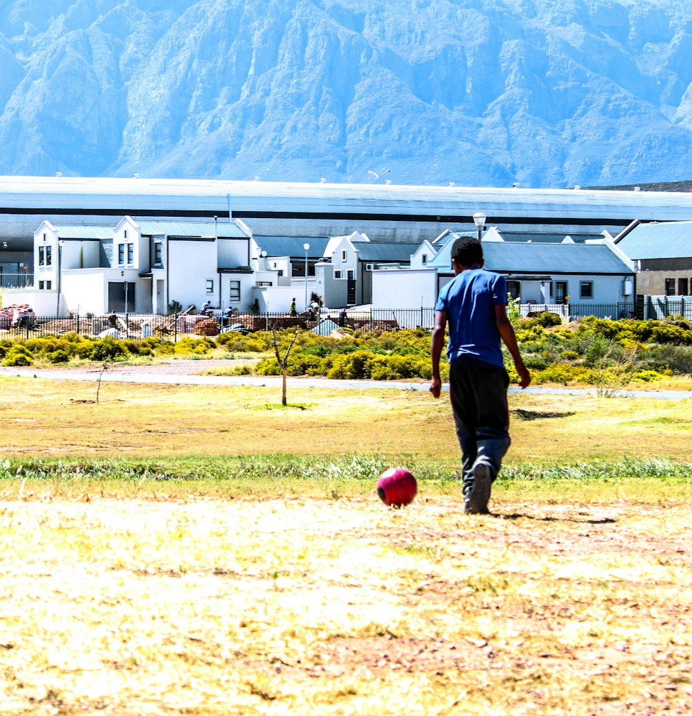 man in black jacket and black pants holding red ball