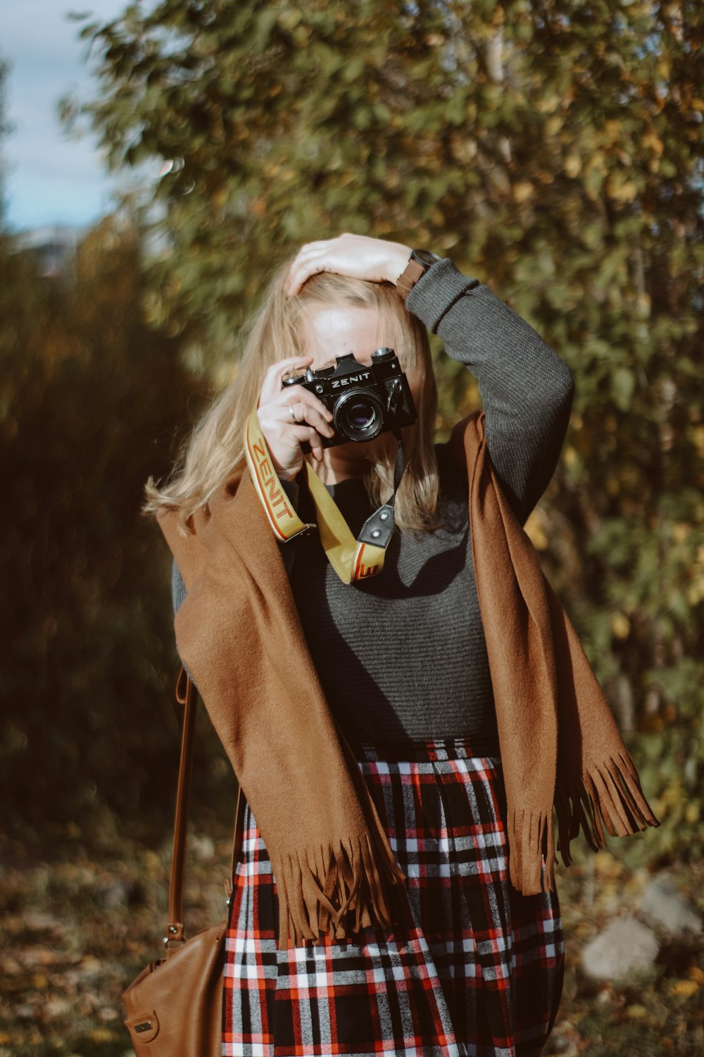 Frau in braunem Mantel mit schwarzer DSLR-Kamera