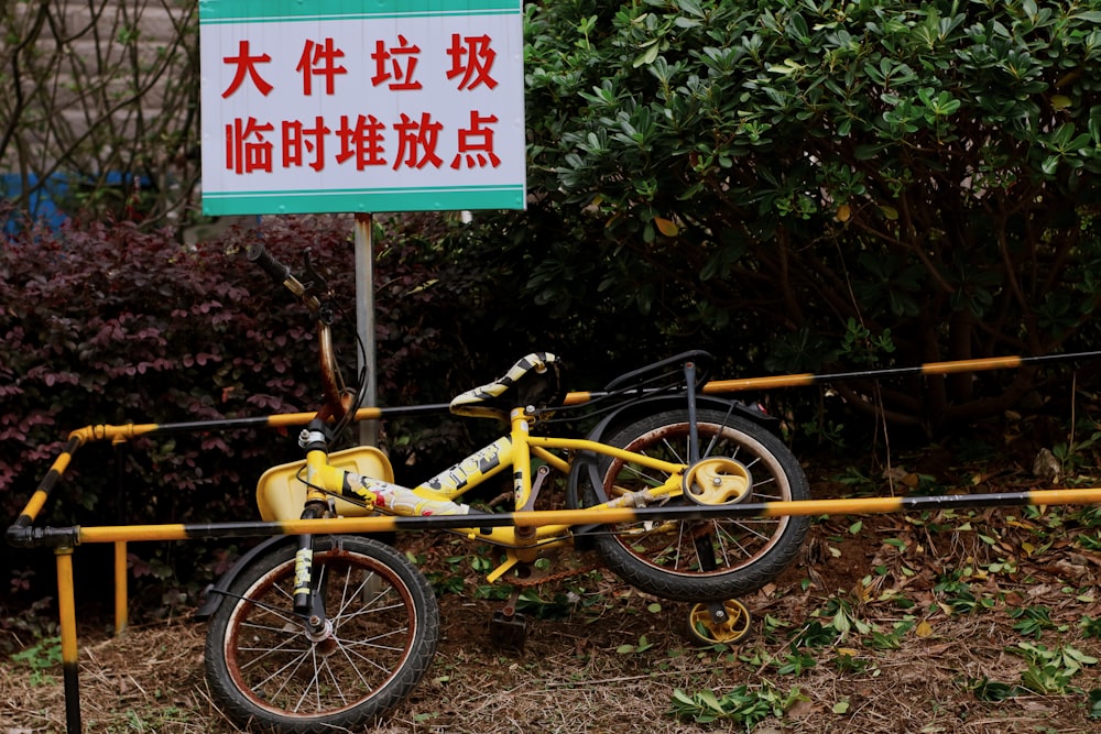 yellow bicycle parked beside green plants