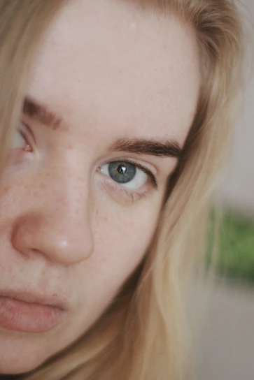 A close-up of a model's face illuminated by soft, artistic lighting highlighting natural textures.