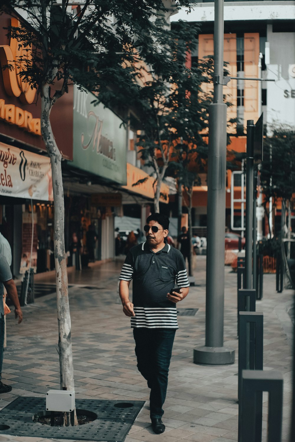 man in black and white striped long sleeve shirt and black pants standing on sidewalk during