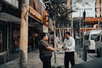 man in white dress shirt and black pants standing on sidewalk during daytime