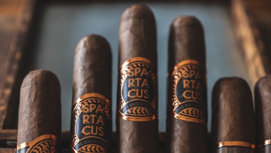 Five cigars are placed in a row, each wrapped with a blue and gold label that reads 