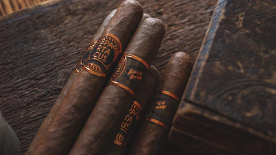 Close-up of a hand-rolled Ahav Humble/Meek cigar resting on a rustic wooden table.