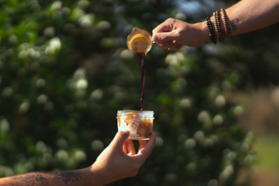 A barista pouring fresh espresso into a ceramic mug with a backdrop of forest greenery.