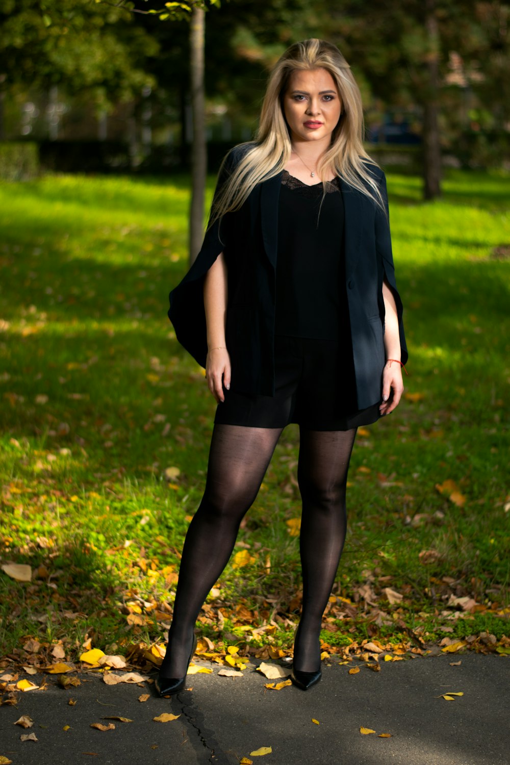 낮 동안 푸른 잔디밭에 서 있는 검은 드레스를 입은 여자