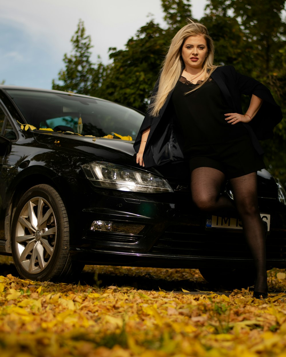 woman in black dress sitting on black car