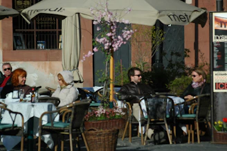 A group of friends enjoying coffee together outdoors in a sunny café setting.