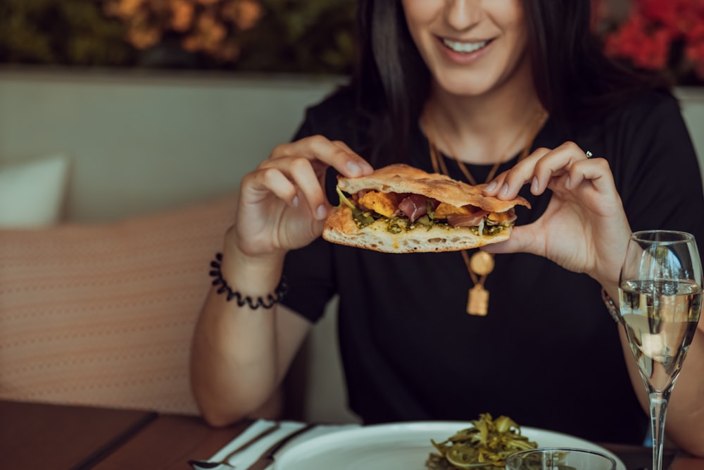 woman in black long sleeve shirt holding a burger