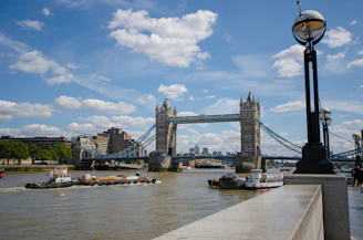 Tower Bridge in London with a clear blue sky, bustling city life around.