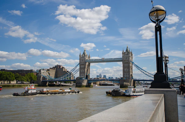 Tower Bridge in London with a clear blue sky, bustling city life around.