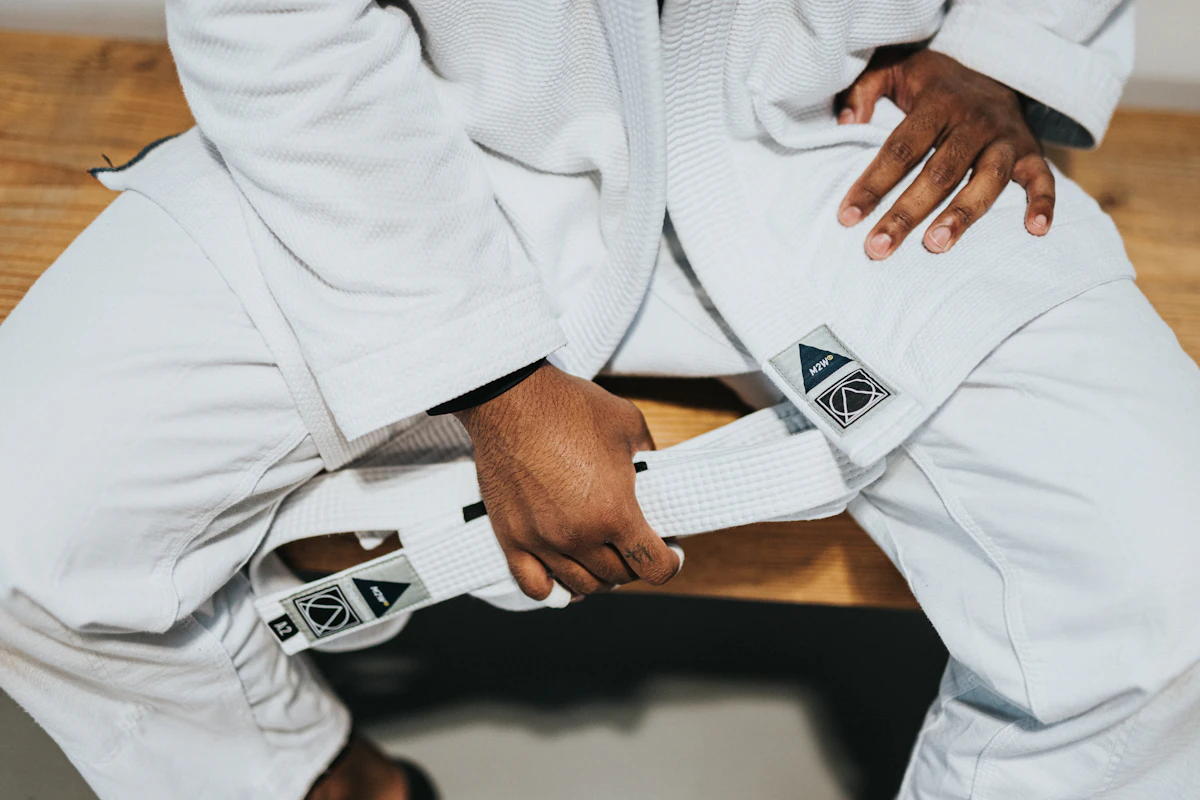 Hands tying a white belt around a white gi