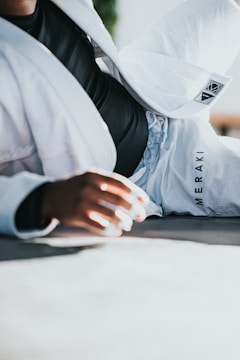A dynamic shot of a BJJ athlete mid-roll wearing branded gear under bright gym lights.