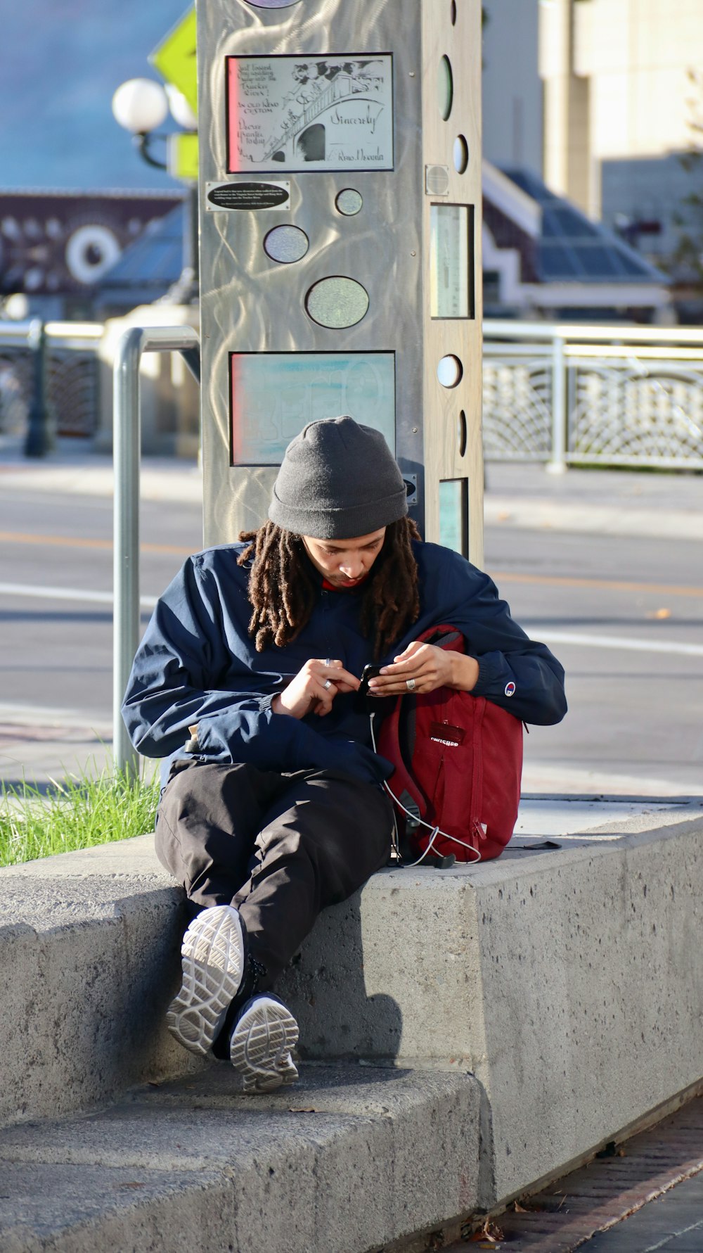 man in black and gray jacket sitting on gray concrete bench