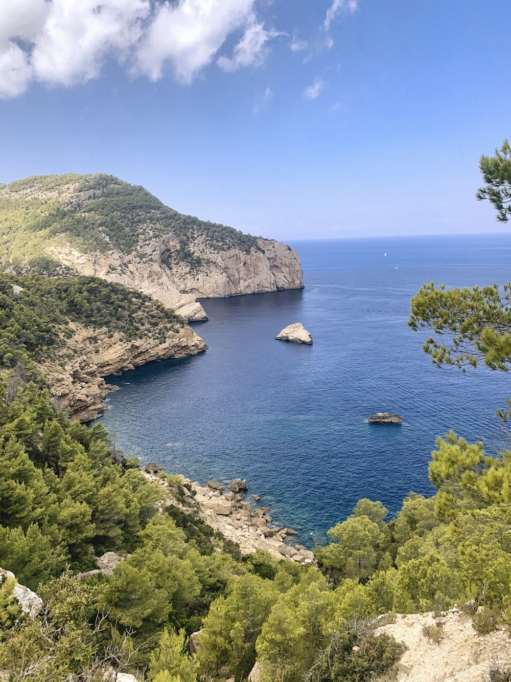 green and brown mountain beside blue sea under blue sky during daytime