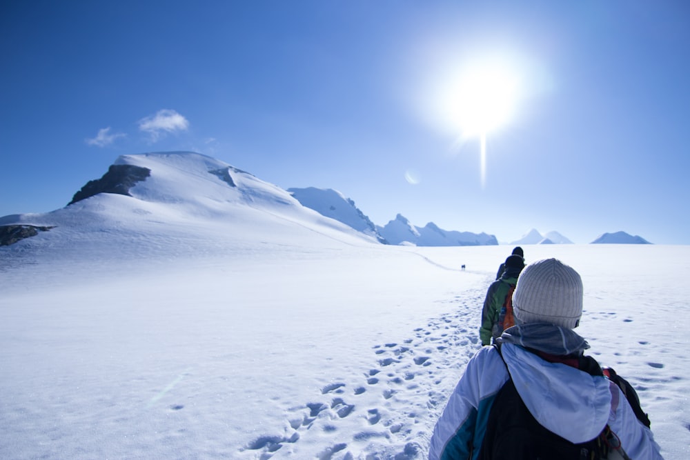 person in green jacket and black knit cap standing on snow covered ground during daytime